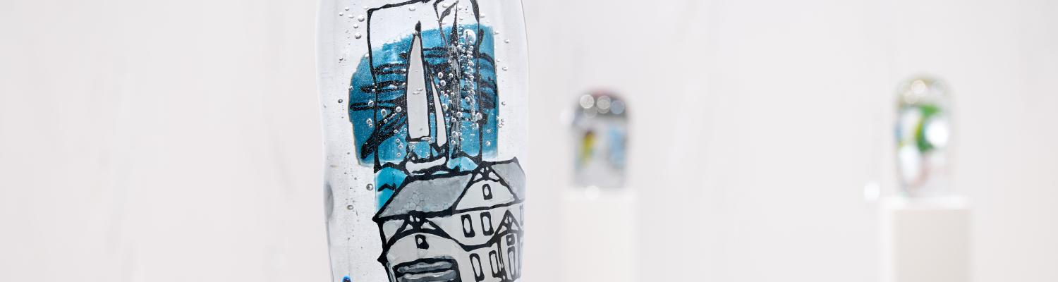 a coastal scene painted within a solid glass column