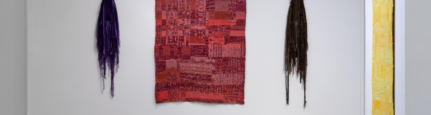 various colorful tapestries adorn the walls of the gallery