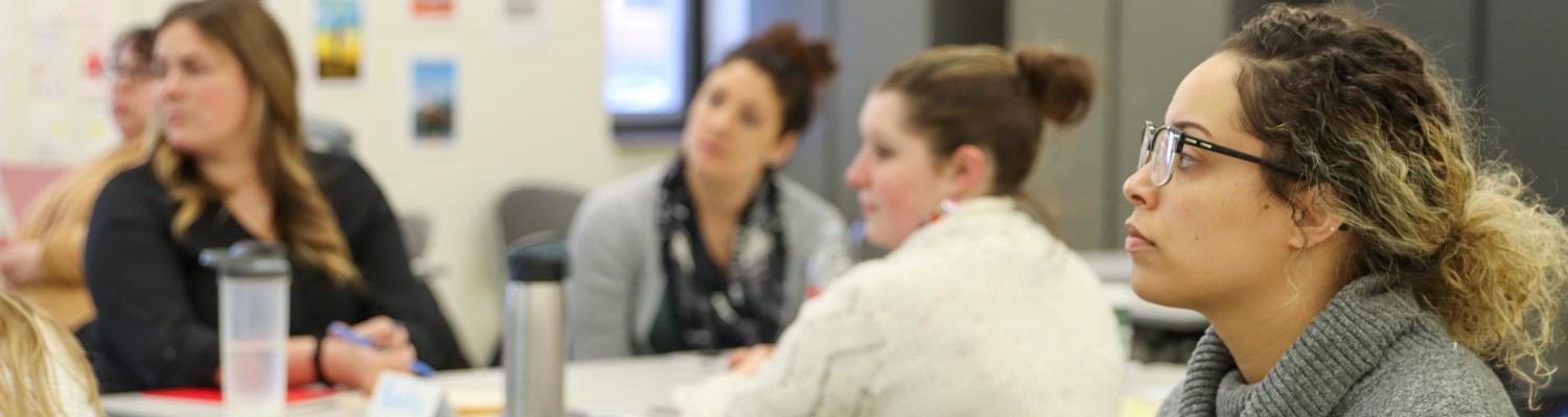 A classroom of Master's students listening to an instructor.