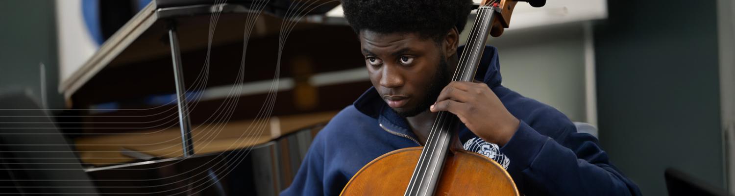 Male wearing a blue shirt playing a string instrument. 