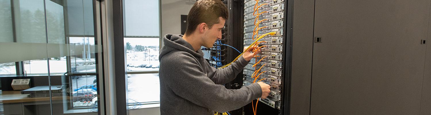 A student adjusts wiring in a server cabinet