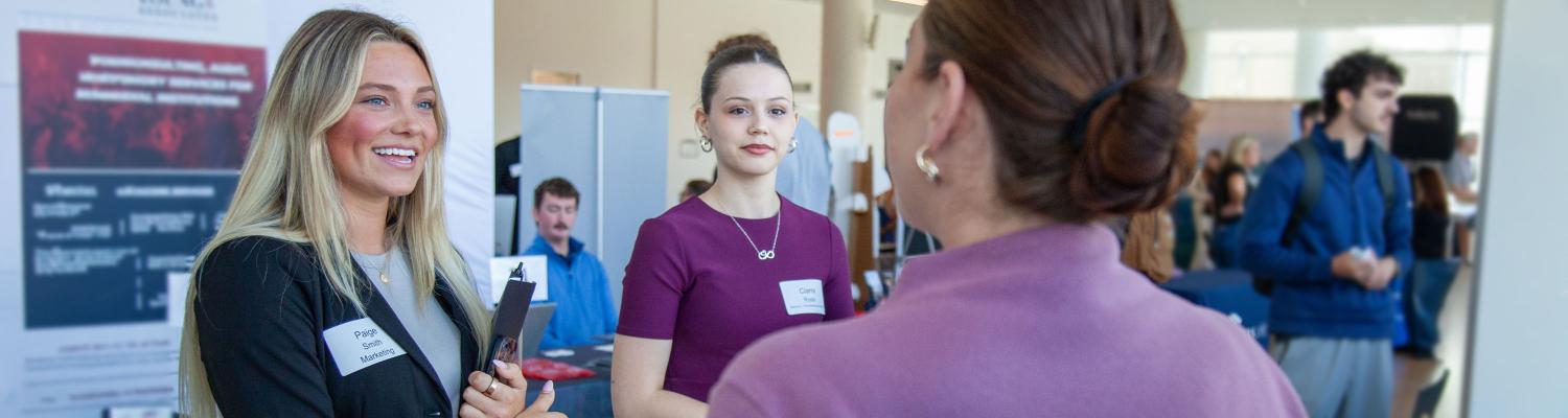 Students smiling and talking with recruiter.