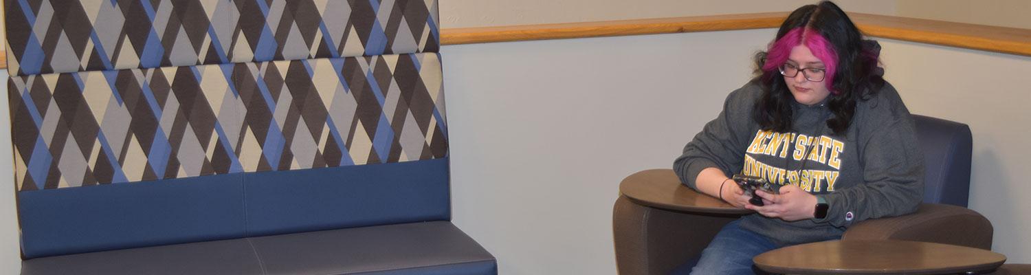 A student looking at their phone between classes in the Lang Learning Loft at ������ East Liverpool.