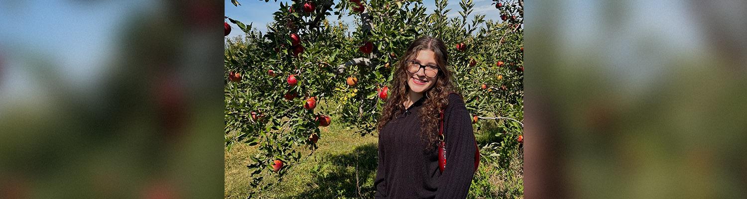 Woman standing in front of apple tree in orchard