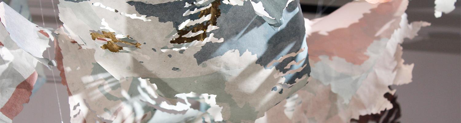 close up shot of print installation with cut out shapes hung across ceiling