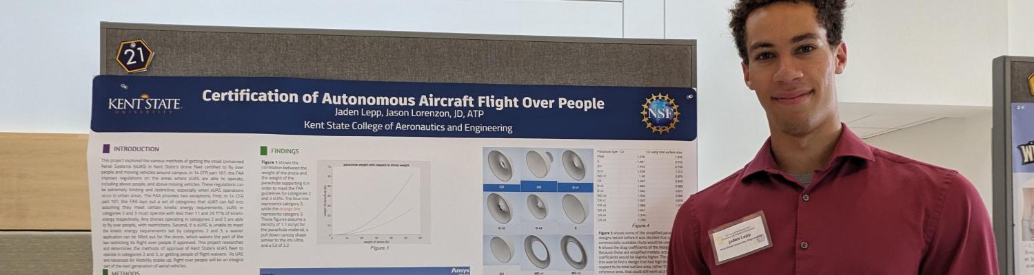 Engineering student Jaden Lepp standing next to a poster describing his project, "Certification of Autonomous Aircraft Flight Over People."