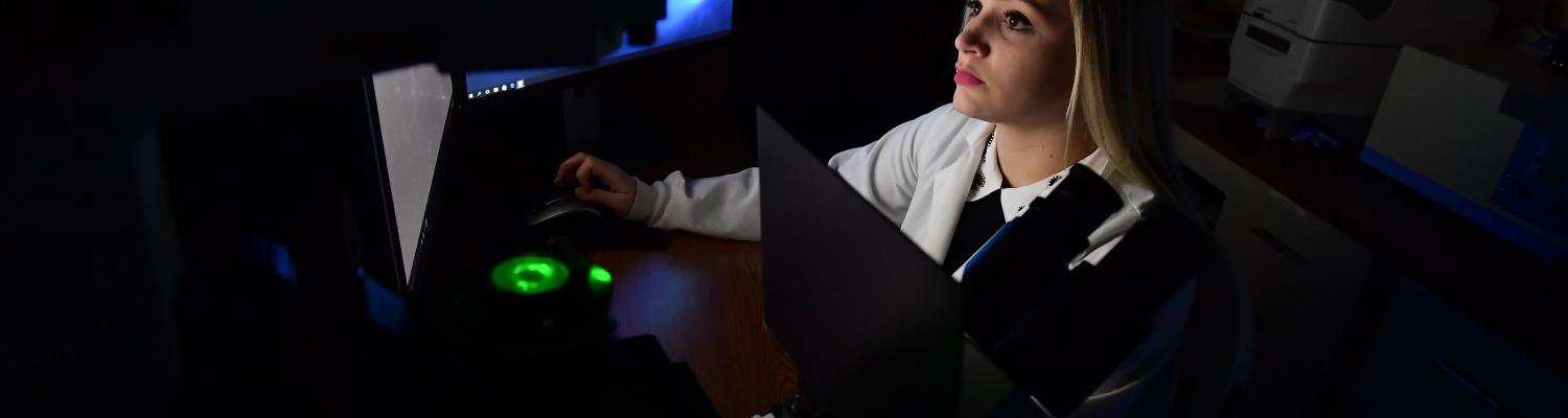 female student in dark room with computer screen
