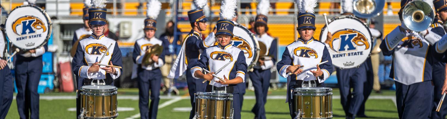 Marching band members playing instruments on the football field