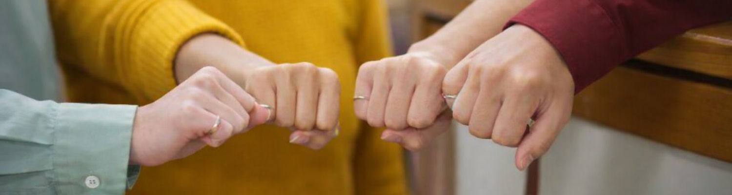Students in a circle with hands extended in front of them showing rings on their fingers. 