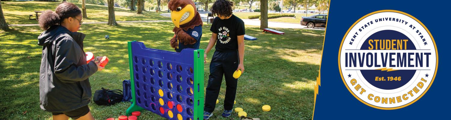 Two students playing Connect Four on the campus lawn