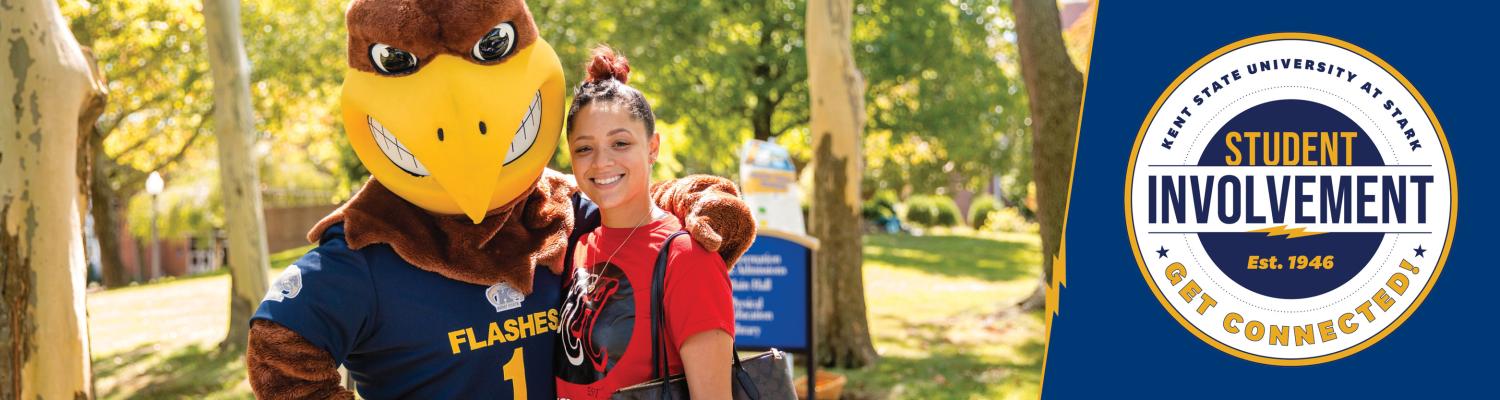 A student posing with Flash the Mascot