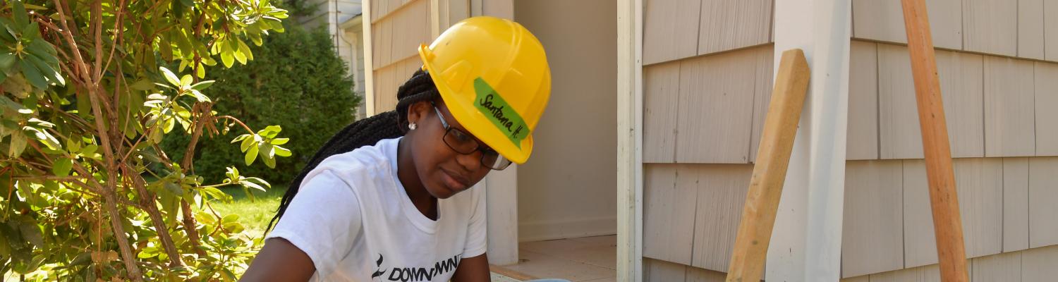 A student engaged in construction work on a Habitat for Humanity house