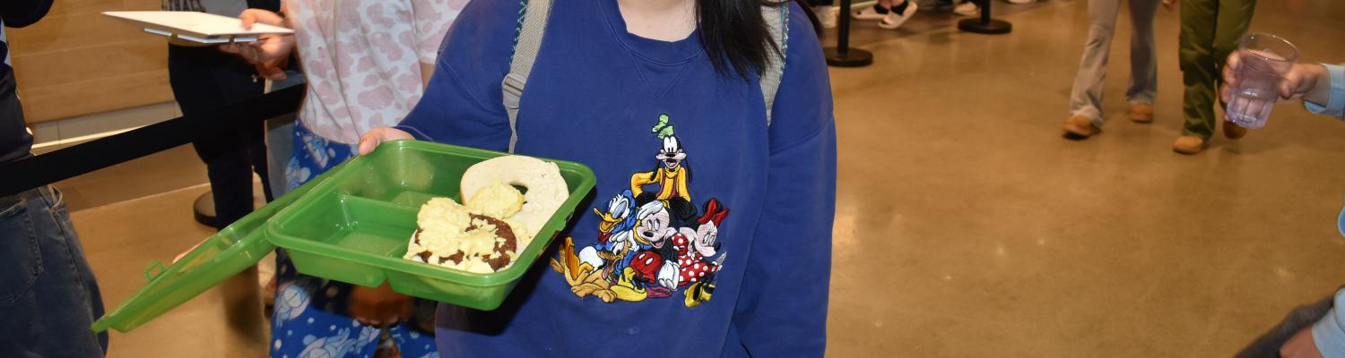 Female KSU Student smiling while holding an open OZZI container filled with food