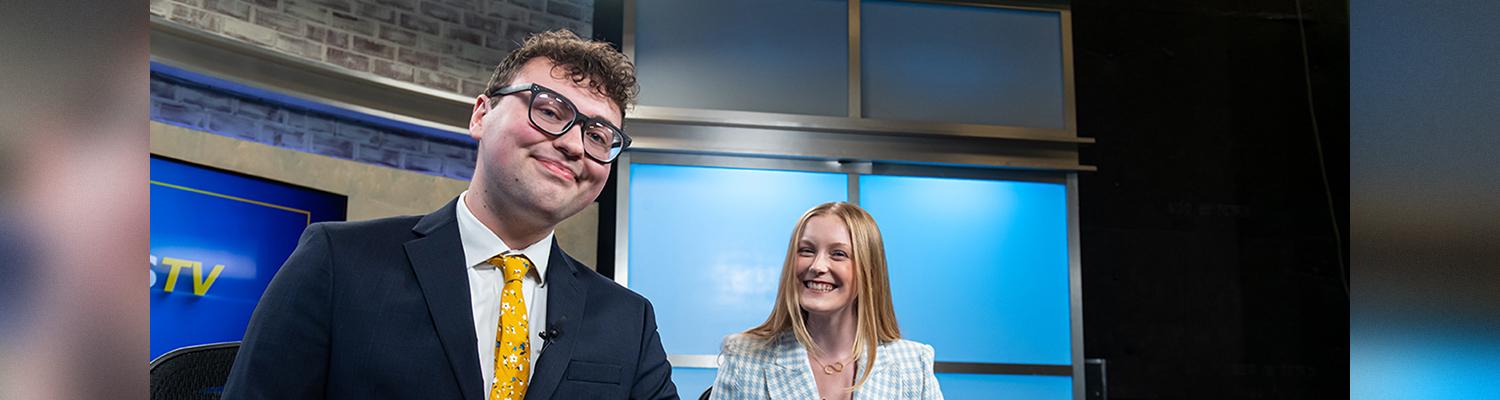 Two tv news anchors for student media smiling at the viewer