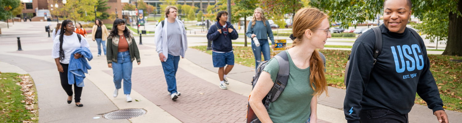 An array of students walk across campus together.