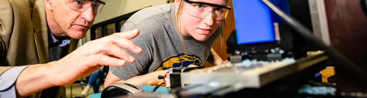Alexis Watson, engineering student, and program director looking at machines