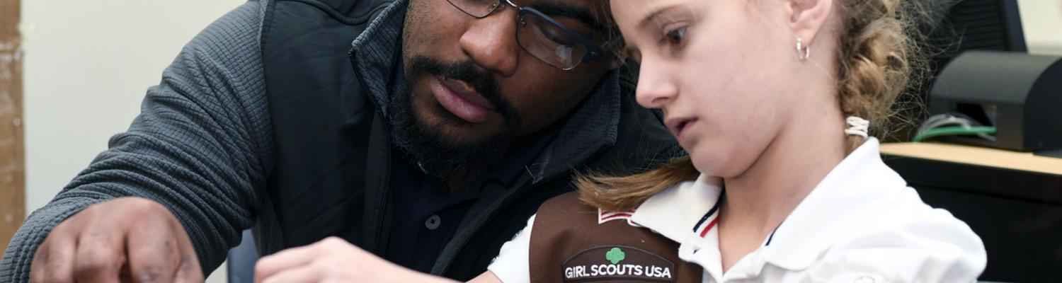 Photo of student and girl scout, working on a project
