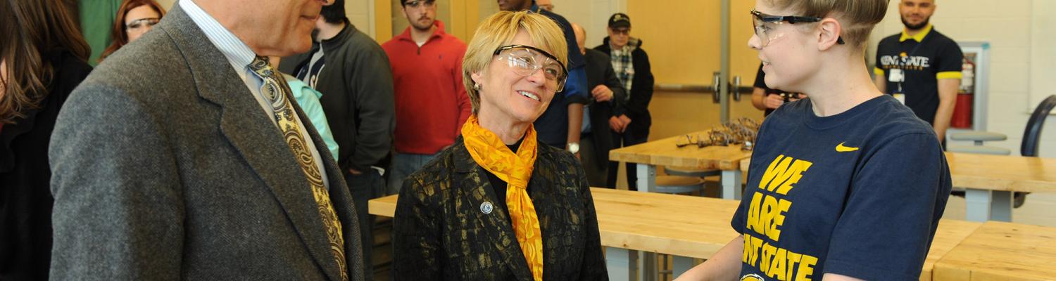Dennis Eckart, chair of the þҹӰԺѹۿ State Board of Trustees and Dr. Beverly Warren speak to a student working in one of the shops in the new Aeronautics and Technology building.