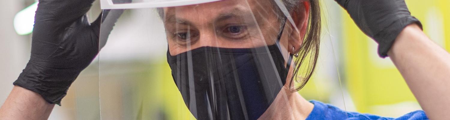 J.R. Campbell, executive director of Kent State University’s Design Innovation Initiative, tries on a face shield produced by the Kent State team.