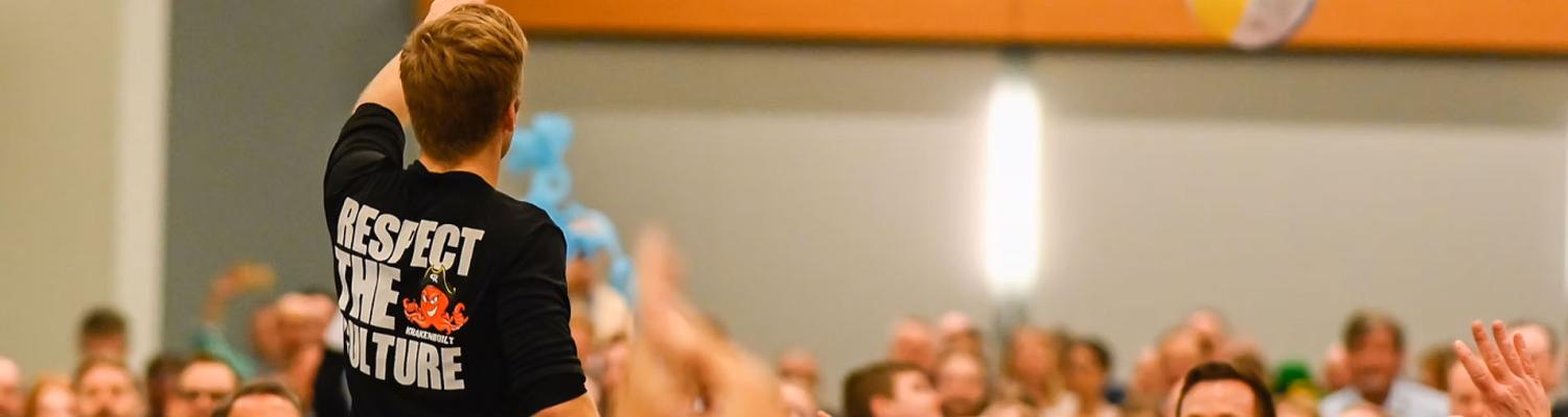Ben Lorenzen standing in a large group of conference participants while beach balls fly through the air above their heads.