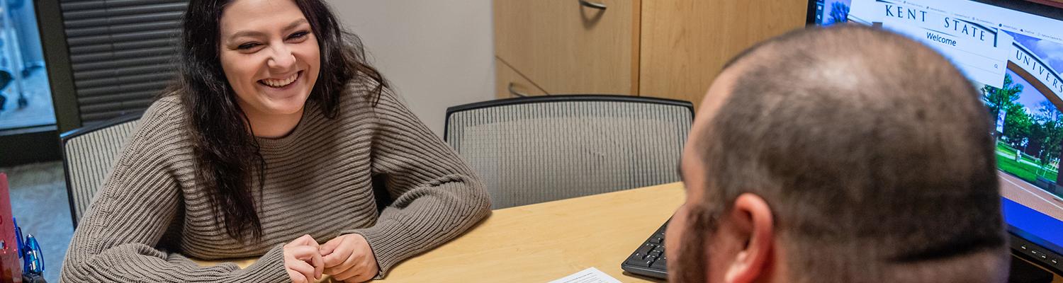 A female student gets assistance with a portfolio from an male advisor