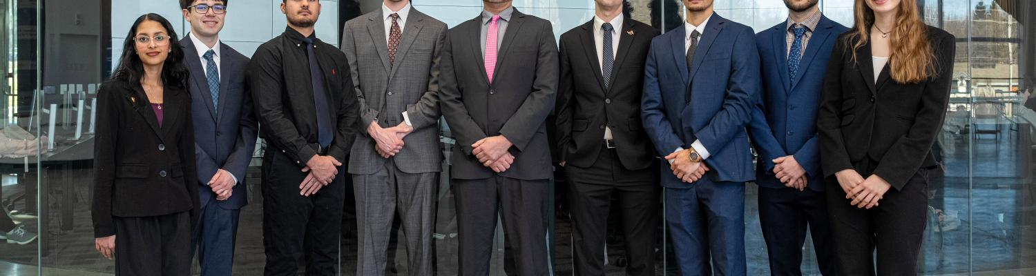The finalists for the 2026 competition standing in business suits in front of the finance lab.