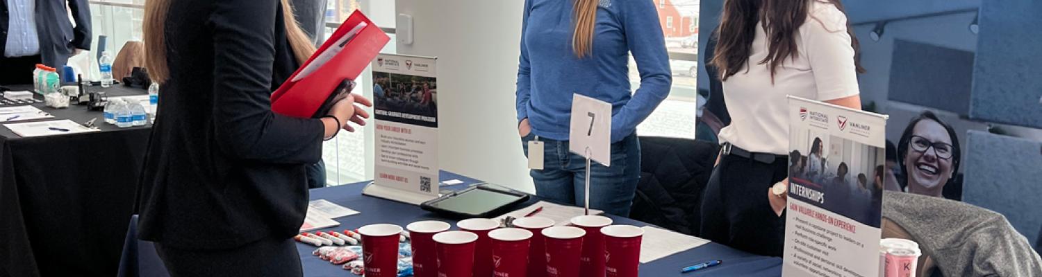 student attending a career fair and chatting with employers. 