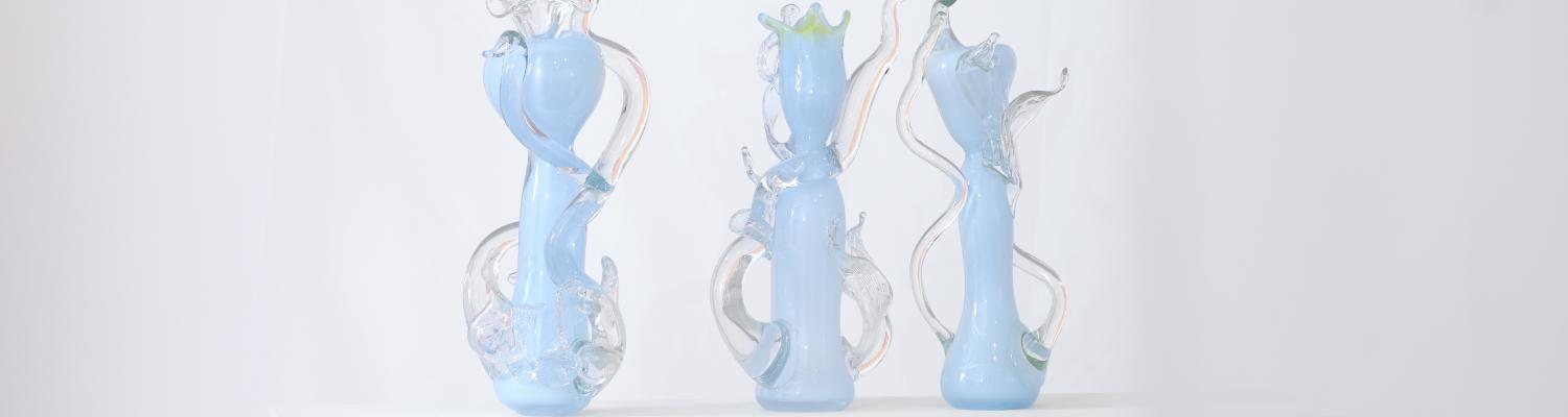 three light blue glass sculptures with clear tendrils on display 