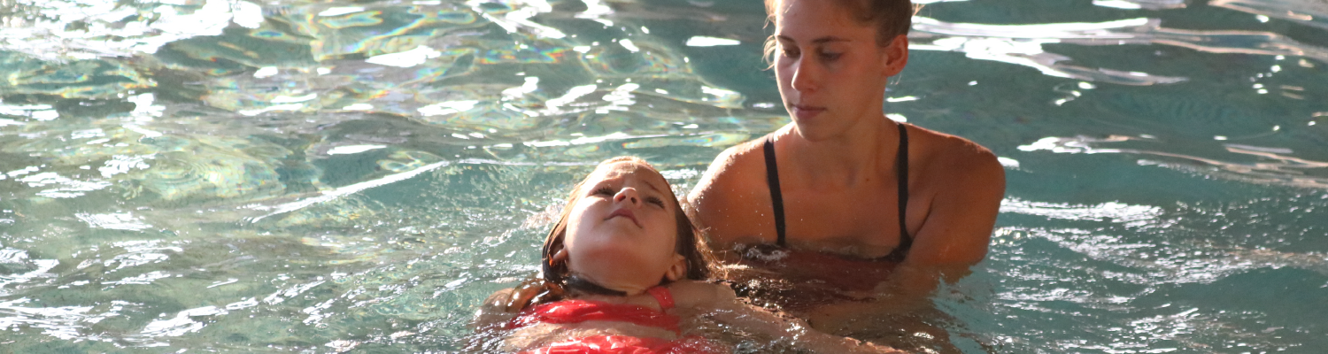 learn to swim instructor with child floating on back