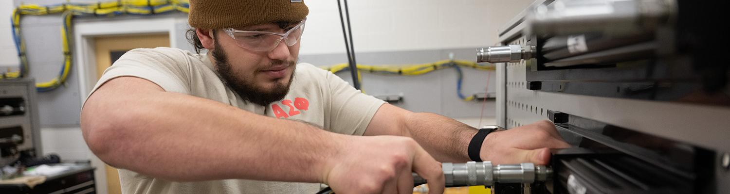 A student secures a hydraulic line to a test fitting