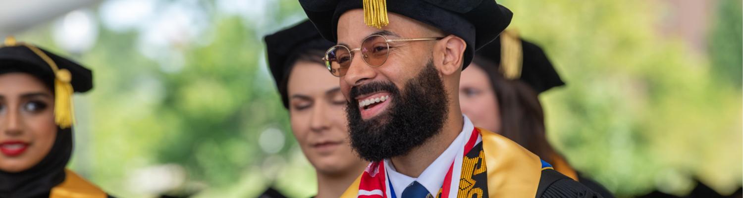 doctoral student smiling at graduation ceremony