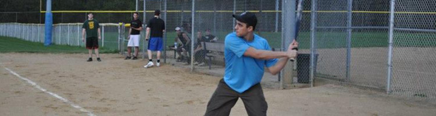 A student gets ready to bat a softball during a night game at the Allerton Sports Complex