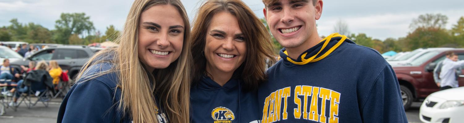 student siblings with parent tailgaiting at football game