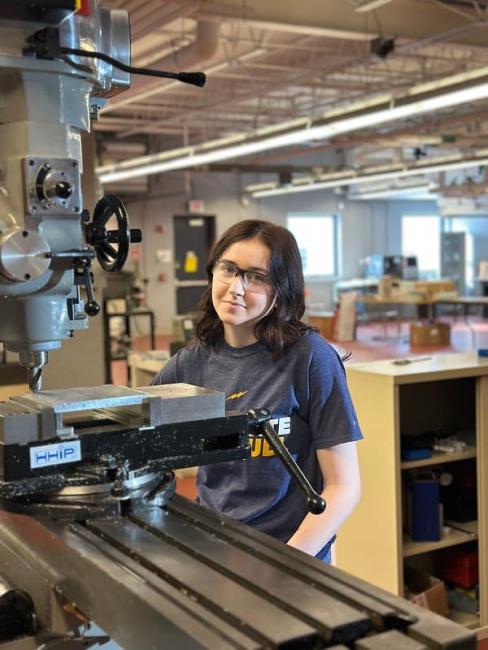 A student doing technical work at a machine