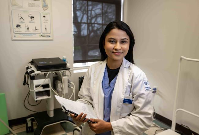 Student in a lab coat holding a clipboard