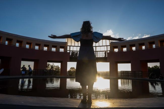 Student with arms out in front of the sun