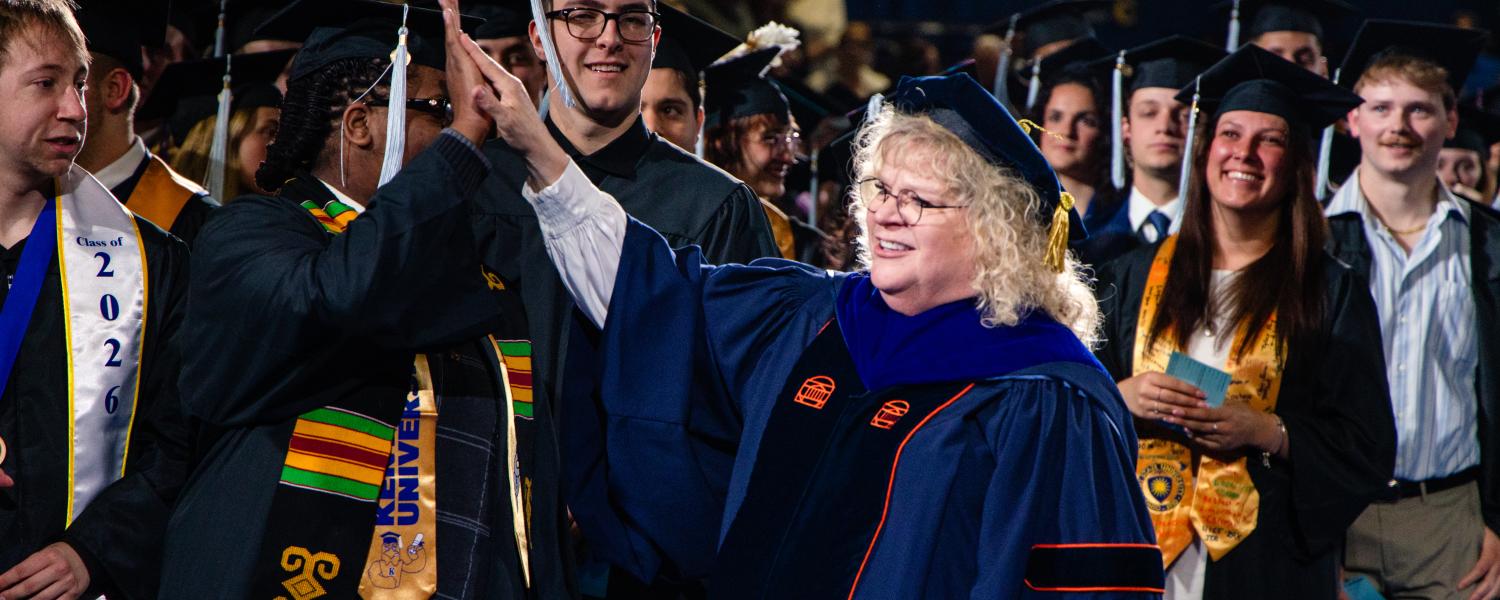 Provost Tankersley in her regalia high-fiving graduates at Commencement 
