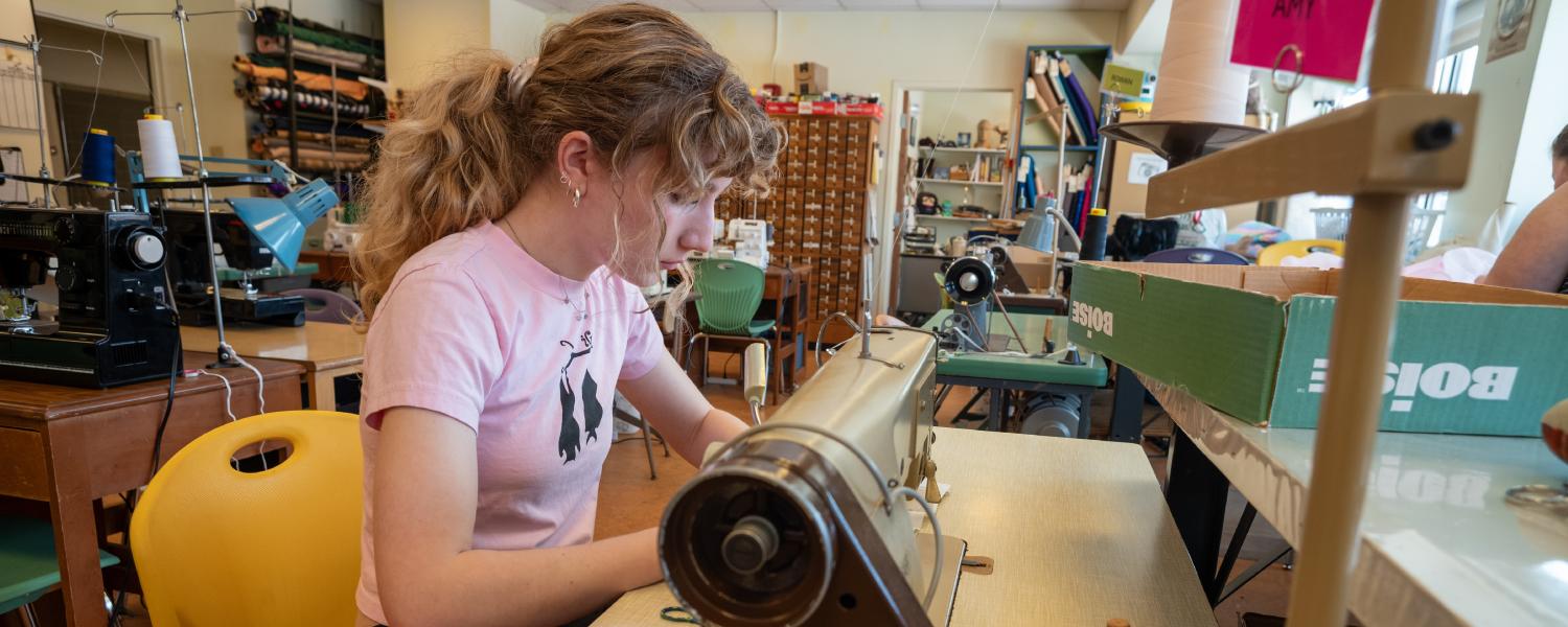 a student works at a sewing machine in the costume shop