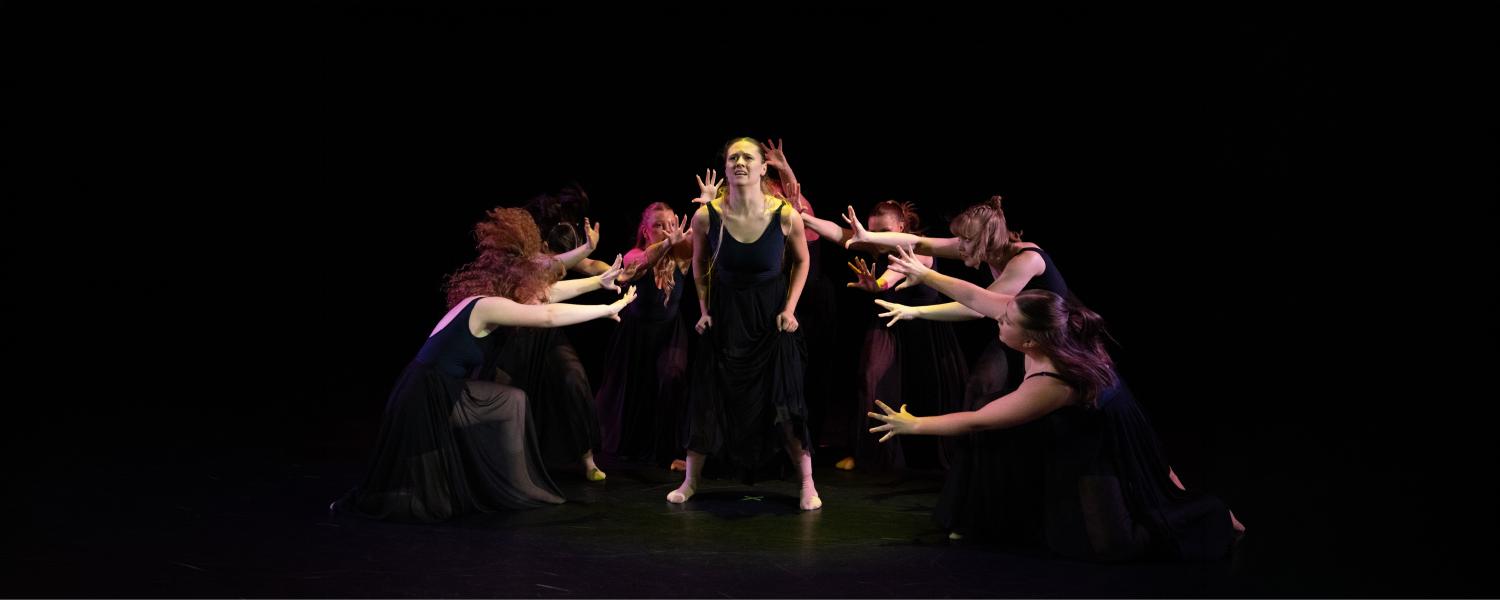 dancers gather around a single dancer on stage