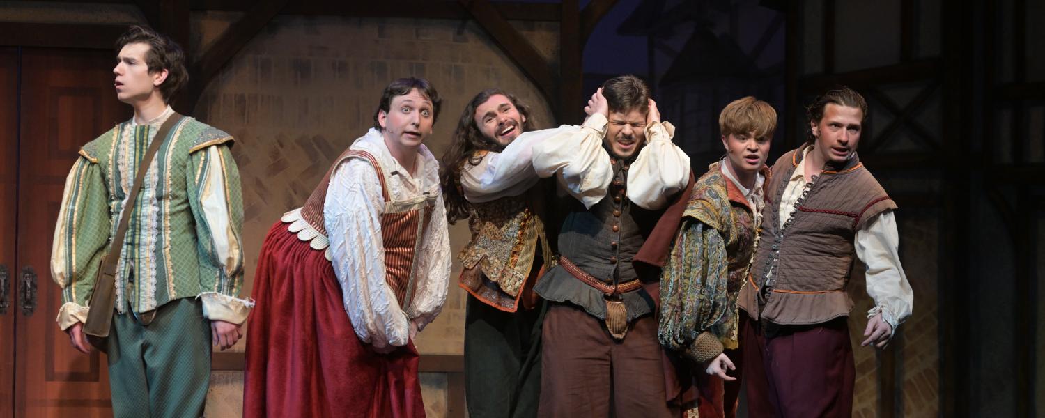 a crowd of actors perform a musical number on stage