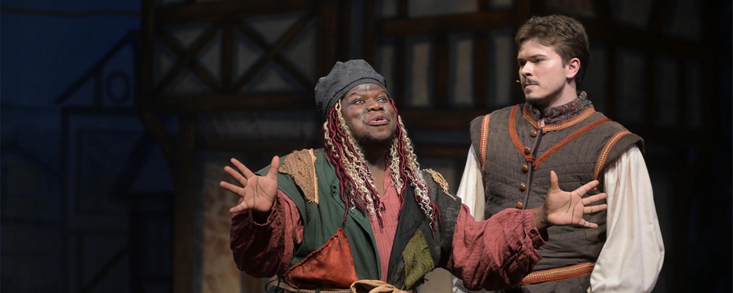 two actors perform on stage with exaggerated expressions