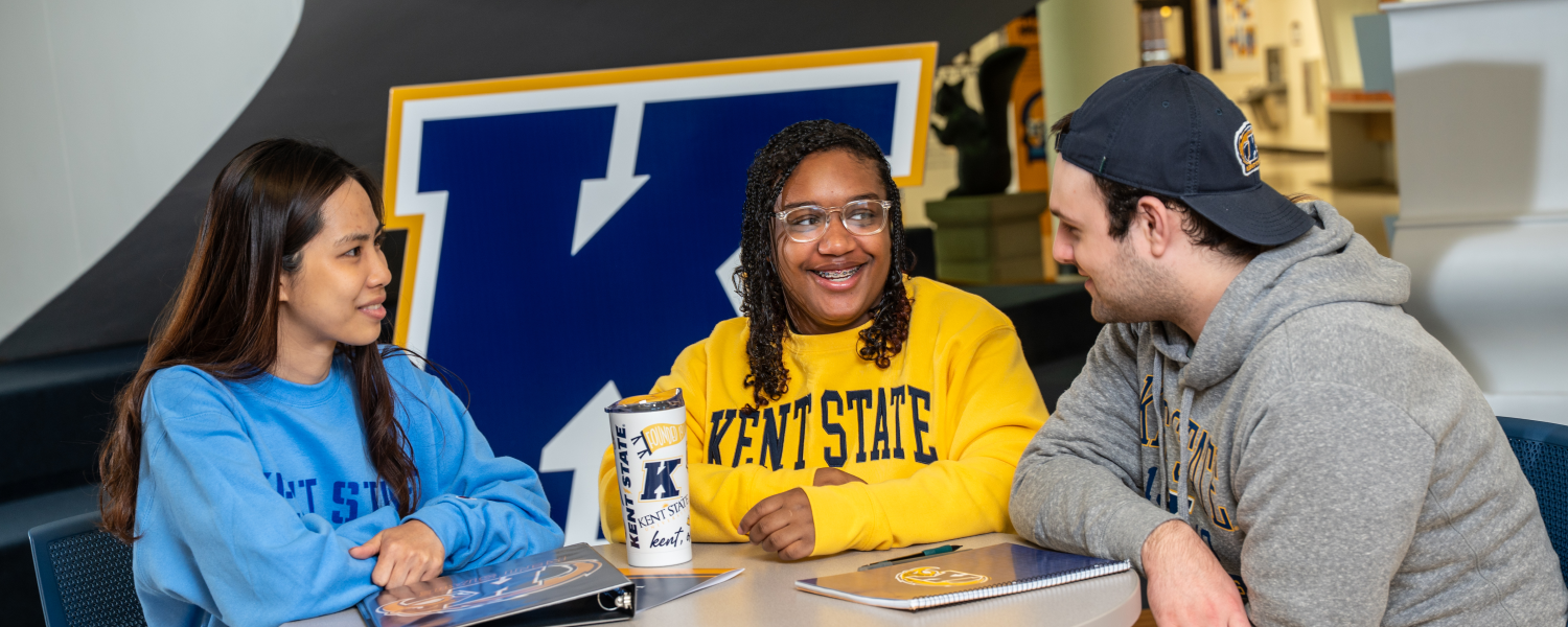 Three students sit around a table in the Kent Student Center.