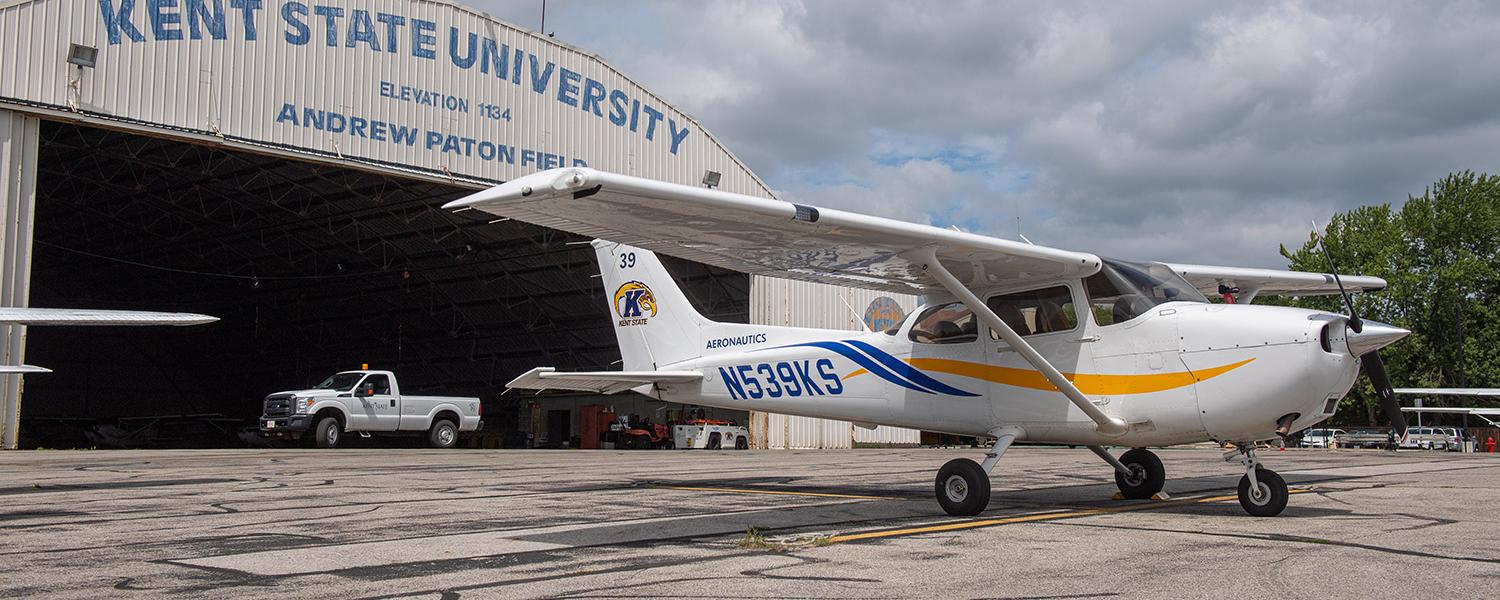 A single-engine airplane parked outside a hangar.