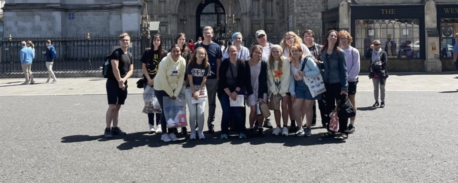 A group of students stands together for a photo in front of a historic building.