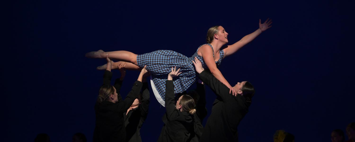 one dancer is lifted by others as she reaches outward