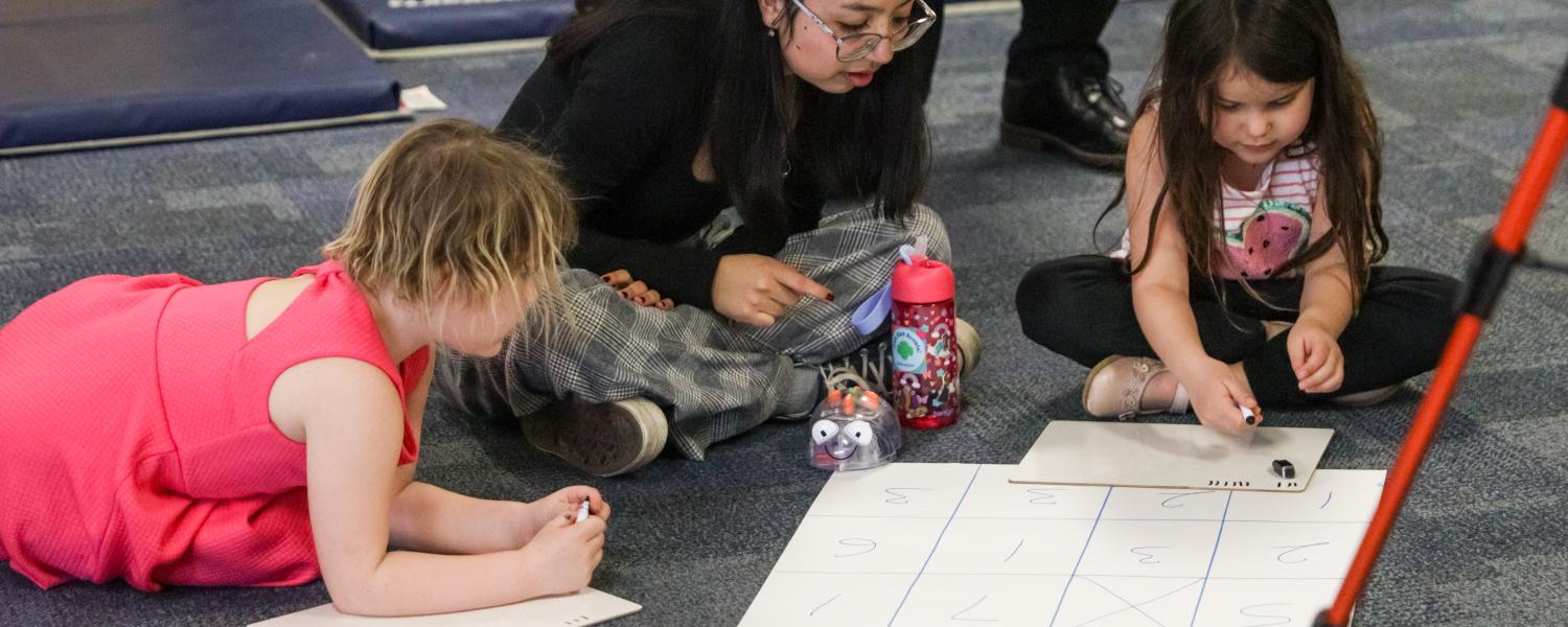 A student working with children in the Child Development Center with coding robots.