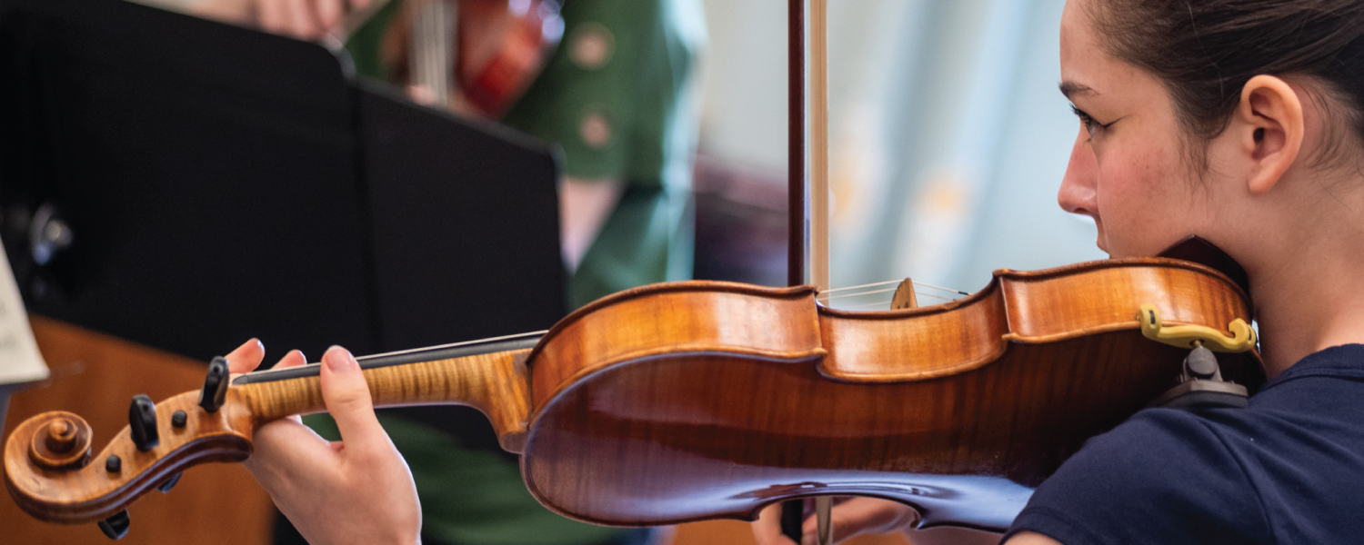 Side profile of a young woman holding a violin to her chin