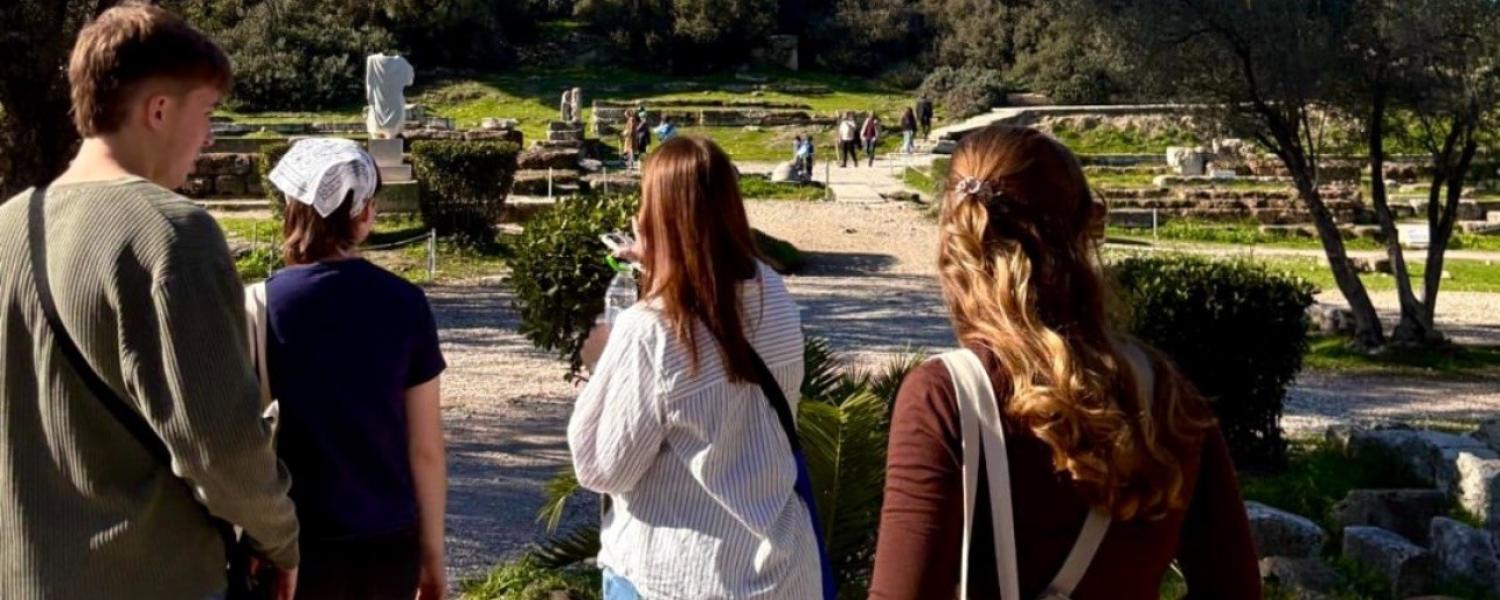 Students walking along a path leading to a large, old stone building.