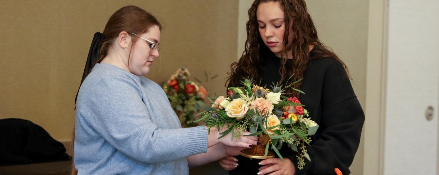 Fockler Leshon and a student prepare a floral arrangement.