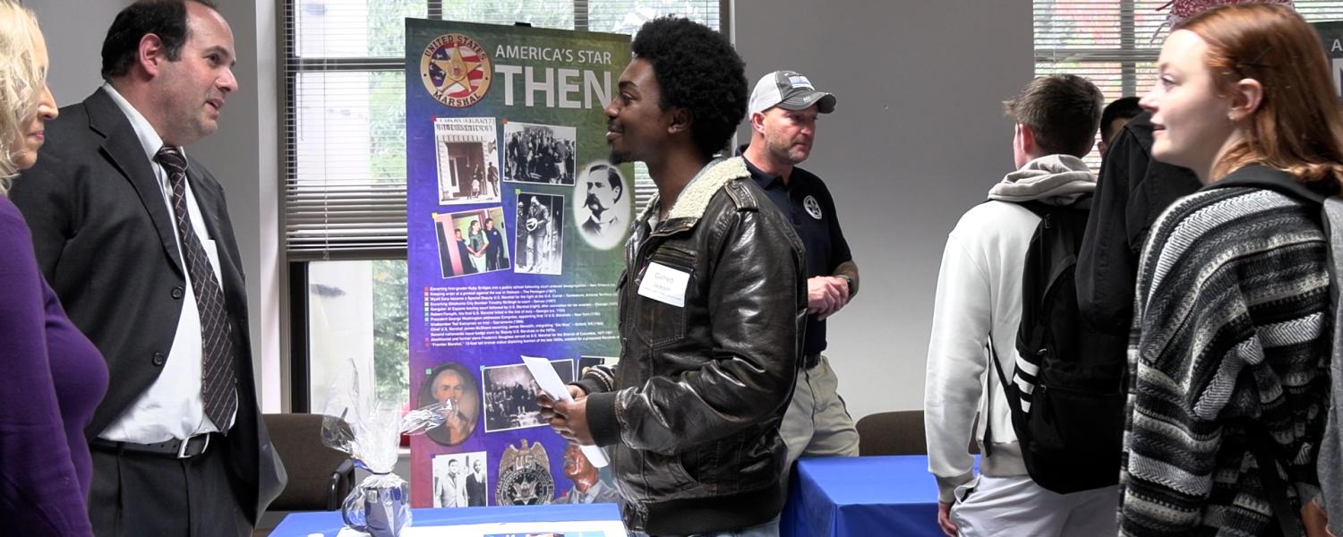Students stand around a table having a discussion about criminology and justice studies
